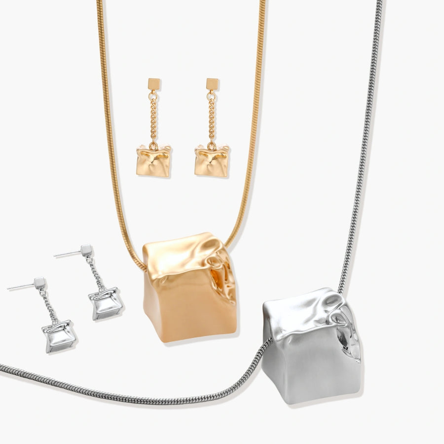 Geometric jewelry set with textured cube pendants on chains, featuring eco-zinc alloy in silver and gold finishes.