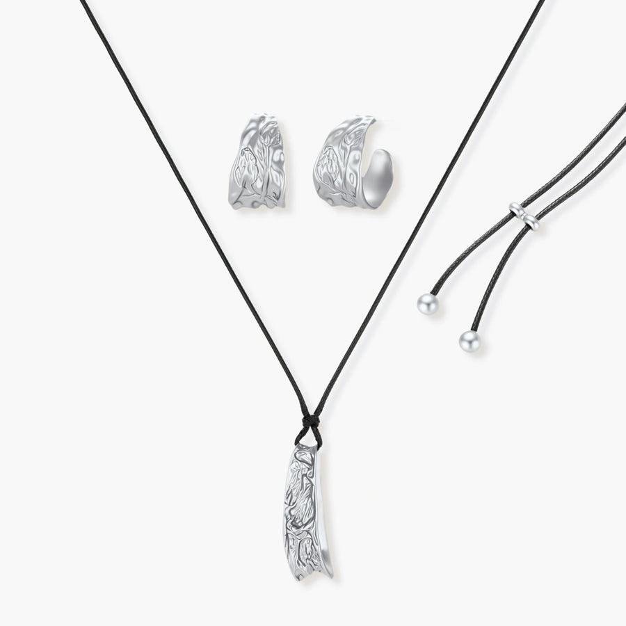 Textured silver jewelry set with floral engravings featuring adjustable cord necklace and matching hoop earrings