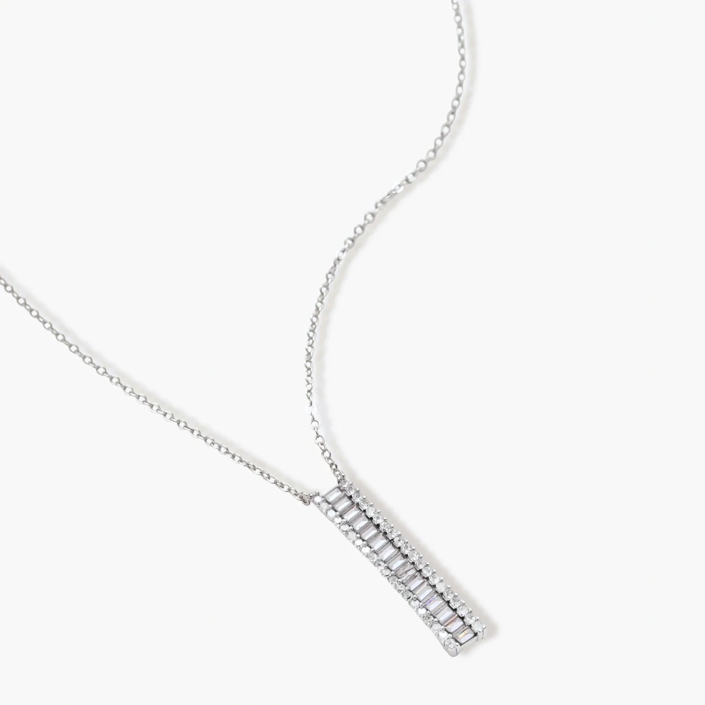 White gold plated necklace with vertical cubic zirconia pendant and matching hoop earrings on neutral background