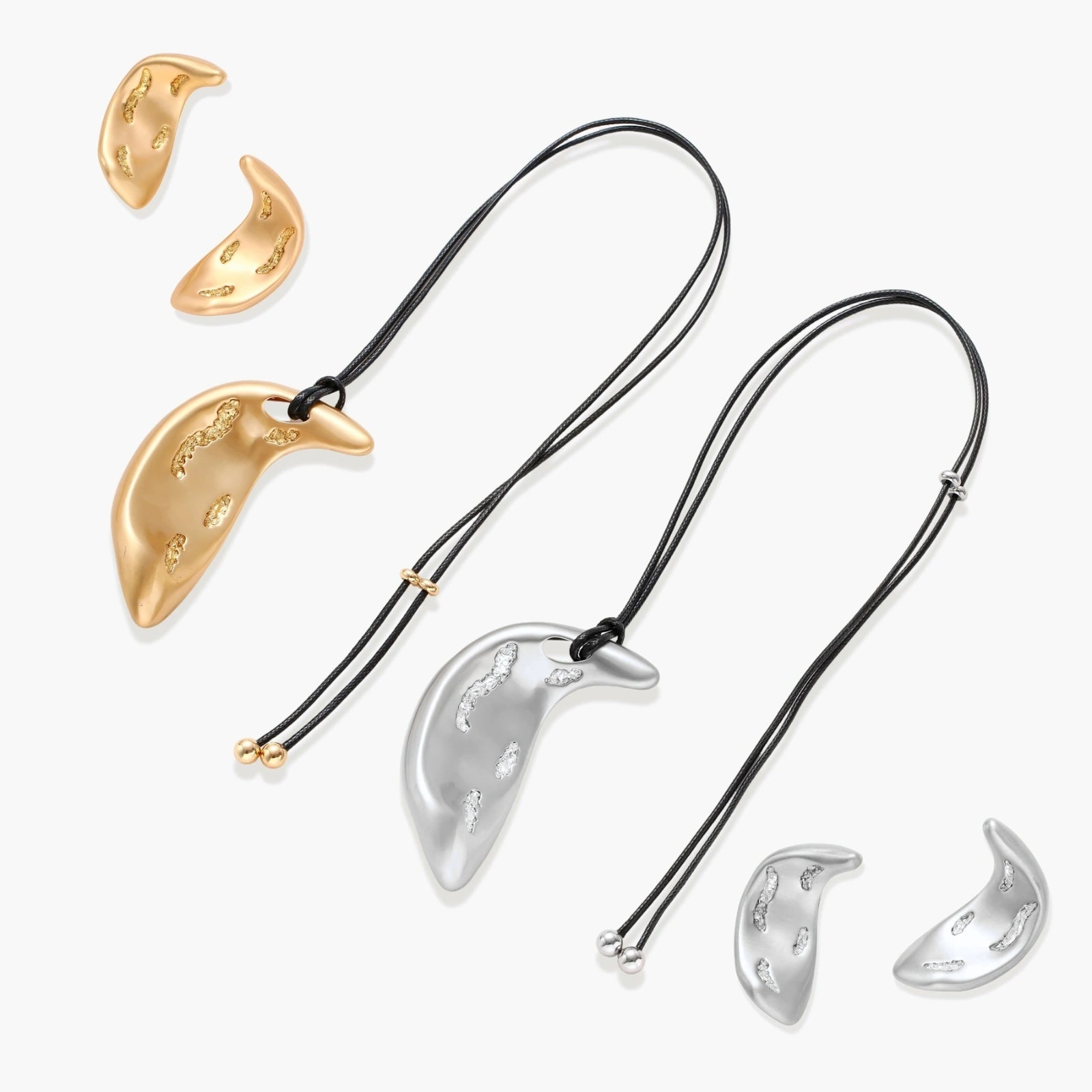 Crescent moon shaped pendant and earrings in eco-zinc alloy with curved crystal inlay patterns on light background.