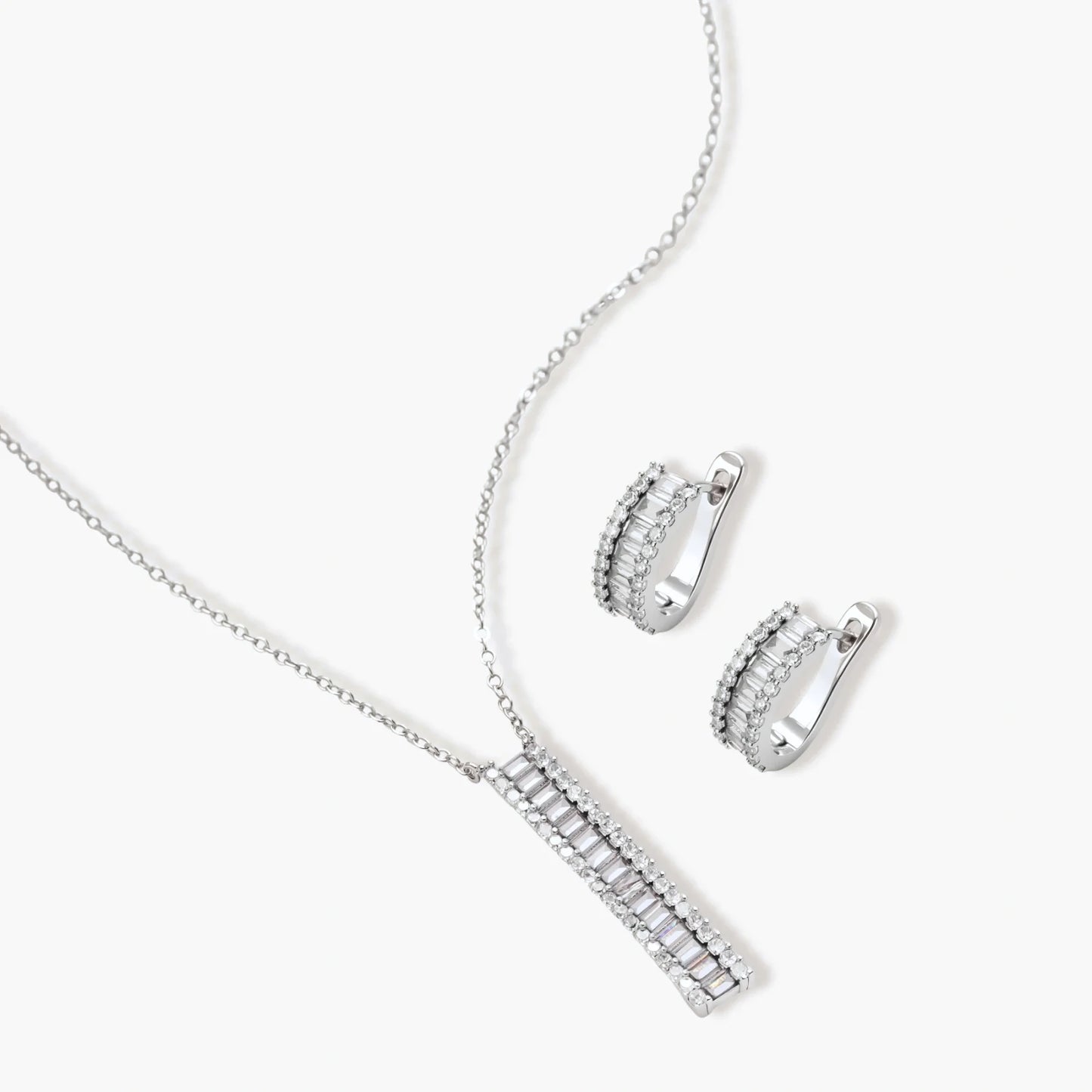 White gold plated necklace with vertical cubic zirconia pendant and matching hoop earrings on neutral background