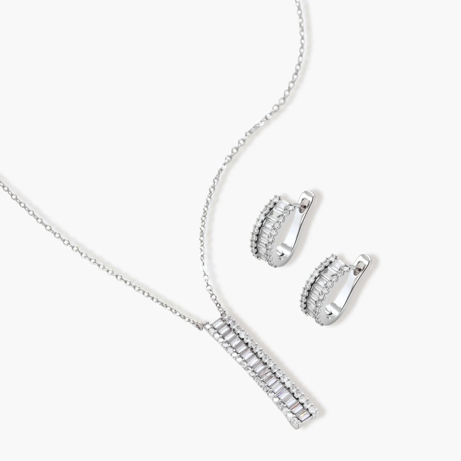 White gold plated necklace with vertical cubic zirconia pendant and matching hoop earrings on neutral background